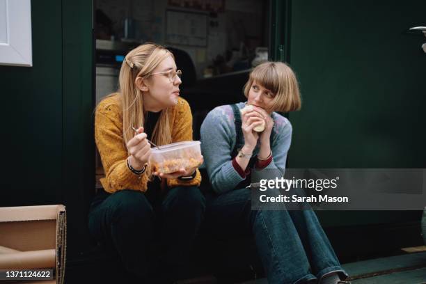 two colleagues sat on step outside office having lunch - lunch lady foto e immagini stock
