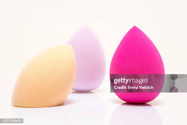 concept the  beauty product foundation multi colored sponges in shape of  easter egg on white  color background, isolated.  easter and beauty minimal concept. trendy color of the year 2022 very peri  lavender. - cleaning sponge stock pictures, royalty-free photos & images
