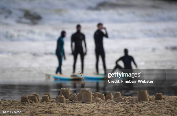 Sandcastles and surfers are seen on the beach, on February 17, 2022 in Bournemouth, England. Travel disruption and power cuts are expected over the...