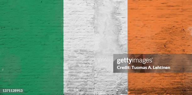 full frame photo of a weathered flag of ireland painted on a plastered brick wall. - republic of ireland flag stock pictures, royalty-free photos & images