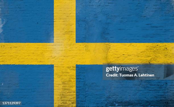 full frame photo of a weathered flag of sweden painted on a plastered brick wall. - swedish flag ストックフォトと画像