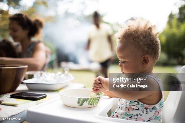 toddler girl eating in high chair on summer patio - black man high 5 stockfoto's en -beelden
