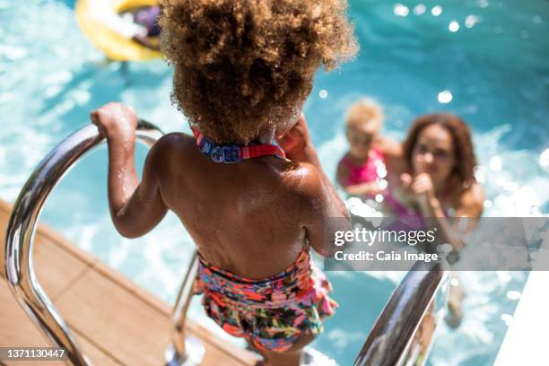 mother watching daughter get into sunny summer swimming pool - leap of faith modo di dire inglese foto e immagini stock