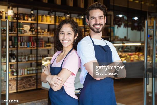 smiling owners back to back with arms crossed - retail occupation stock pictures, royalty-free photos & images