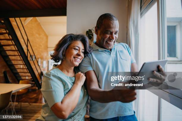 mature couple  using digital tablet at home - mid adult stock pictures, royalty-free photos & images