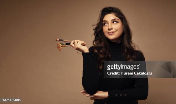 portrait of cute beautiful young woman holding makeup brushes. - makeup artist stock pictures, royalty-free photos & images
