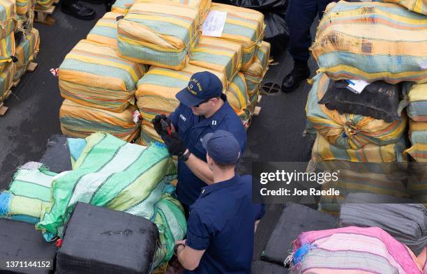 Coast Guard personnel walk among wrapped packages of cocaine and marijuana on the deck of the Cutter James before offloading them at Port Everglades...