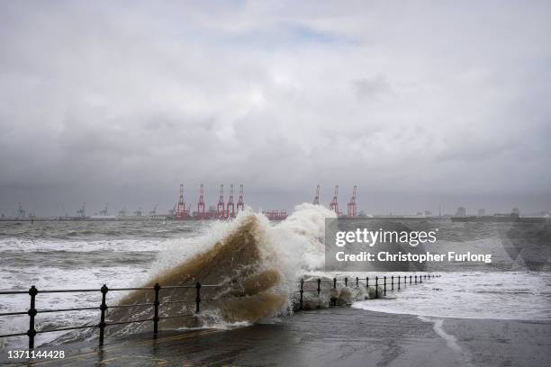 People view the waves created by high winds and spring tides hitting the sea wall at New Brighton promenade on February 17, 2022 in Liverpool,...