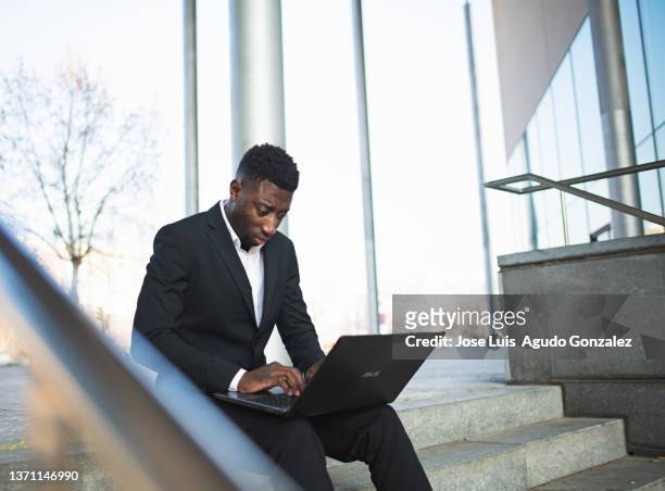smart african american entrepreneur browsing laptop on stairs - laptop netbook fotografías e imágenes de stock