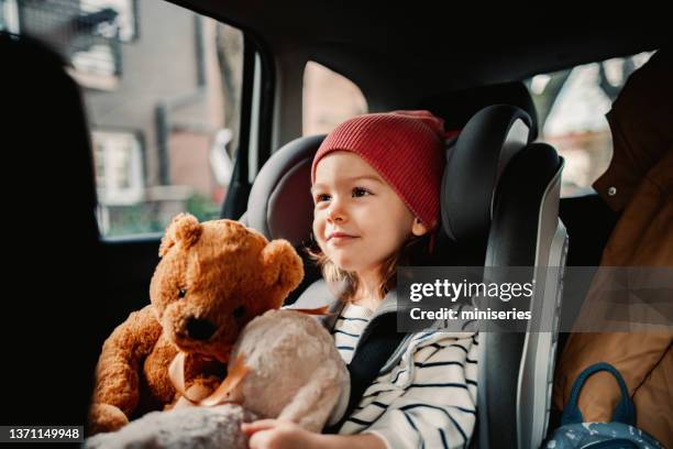 bambina che tiene il suo giocattolo preferito mentre viaggia in auto - pink belt foto e immagini stock