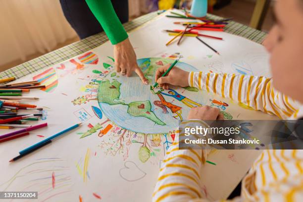creative schoolboy with a help of teacher making the art about sustainability - learning generation parent child stock pictures, royalty-free photos & images