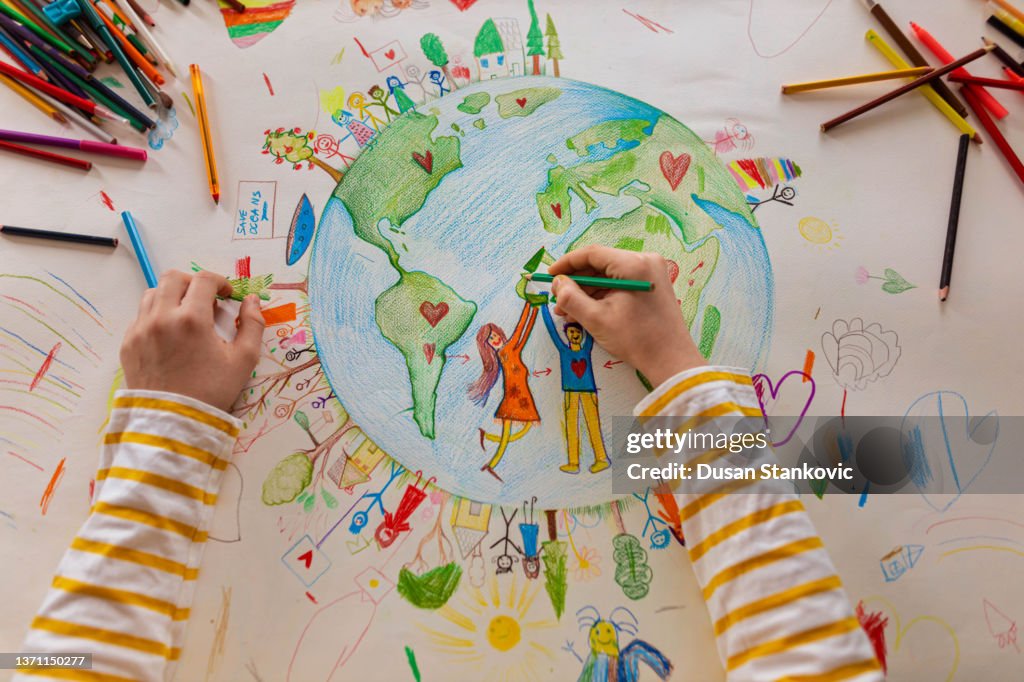 High angle view of unrecognizable boy draw the planet Earth with people