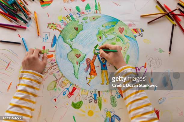 high angle view of unrecognizable boy draw the planet earth with people - kids creativity imagens e fotografias de stock