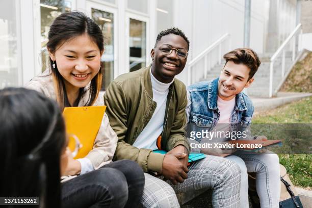 multiracial group of young teenage people hanging out at university campus - ethnische zugehörigkeit stock-fotos und bilder