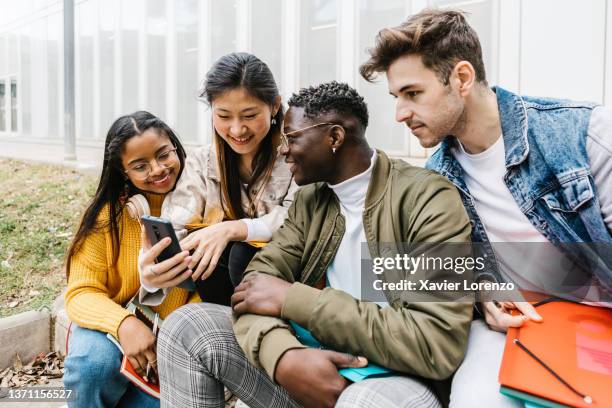 young multiracial student friends sharing content on social media thought mobile phone app - 同等 個照片及圖片檔