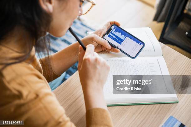 imprenditrice che analizza il mercato azionario finanziario su smartphone - certificato azionario foto e immagini stock
