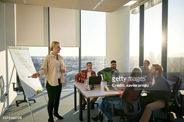 project manager discussing plans with team in modern office - estratégia de negócio imagens e fotografias de stock