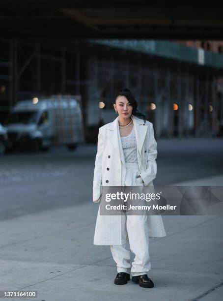 Jessica Wang wears silver earrings, a silver chain necklaces, a white with small blue letter print pattern V-neck tank top from Peter Do, a matching...