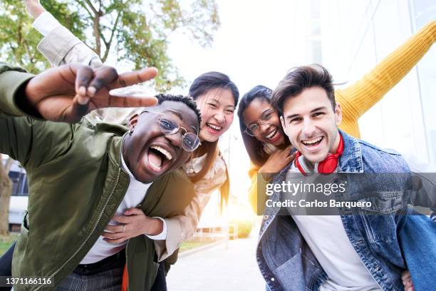 happy portrait of four friends having fun doing piggyback to women. - students union stock pictures, royalty-free photos & images