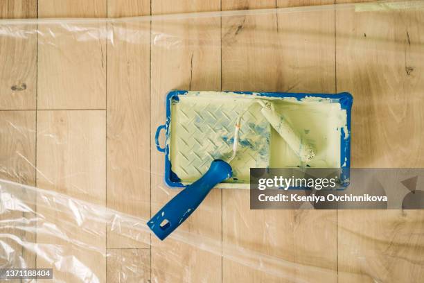 still life of paint roller in tray on wood floor. - paint tray fotografías e imágenes de stock