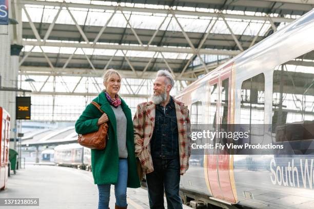 vibrant senior couple walking on train station platform - couple train stock pictures, royalty-free photos & images