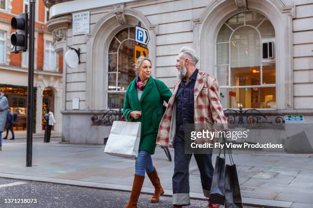senior couple on european vacation cross city street - mature couple winter outdoors stockfoto's en -beelden