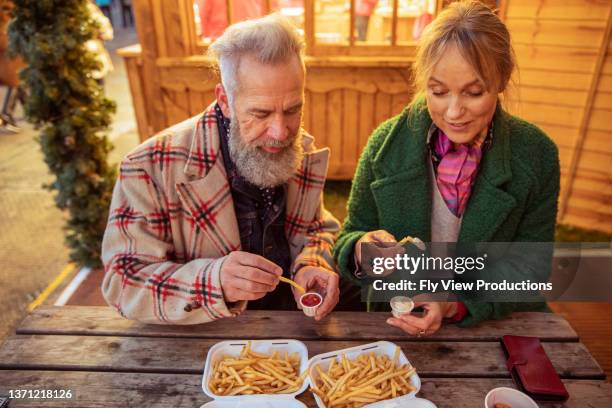 älteres touristenpaar, das street food genießt - boomer couple out on town stock-fotos und bilder