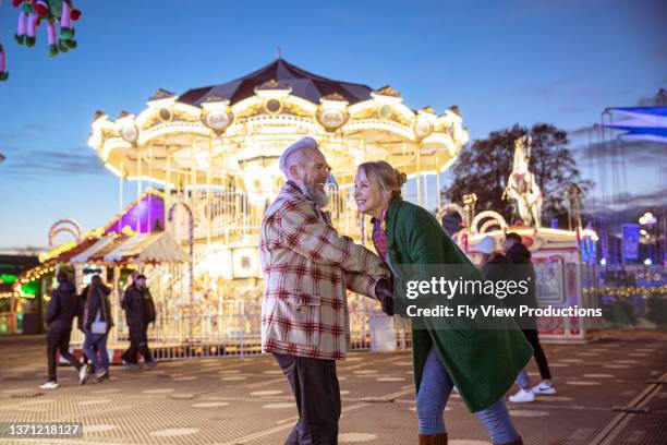 carefree couple dancing at street festival - mature couple winter outdoors stock pictures, royalty-free photos & images