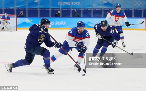 Marek Hrivik of Team Slovakia controls the puck between Sakari Manninen and Markus Granlund of Team Finland in the third period during the Men's Ice...