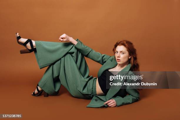 fashionable woman posing in the studio on a colored brown background in the studio. the concept of fashion and clothing sale. - wide leg trousers stock pictures, royalty-free photos & images