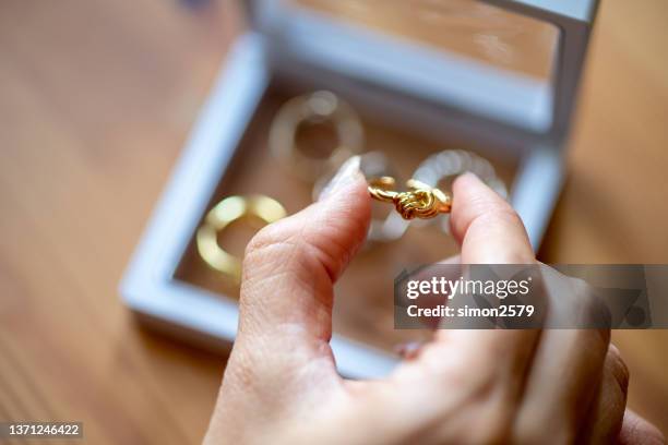 women's hands choosing golden ring from her jewelry box - build presents sensitive skin imagens e fotografias de stock