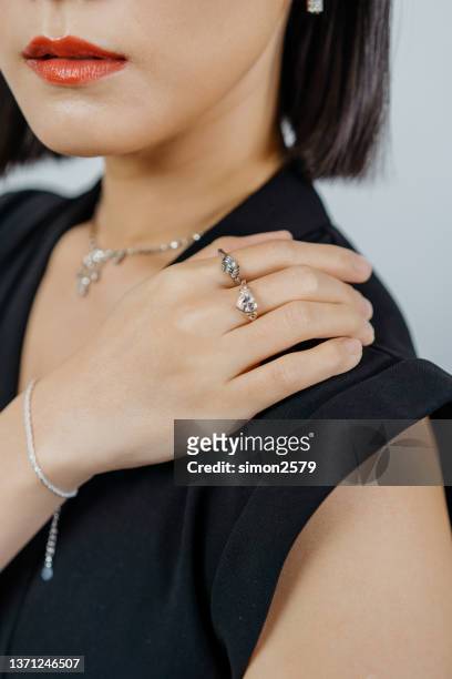 portrait of beautiful asian woman dressed in a posh jewelry set of diamond ring, bracelet and earrings - skin diamond stockfoto's en -beelden
