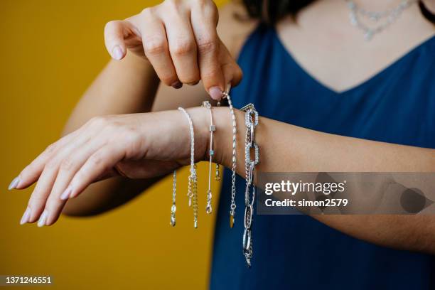 close-up shot of women's choose silver bracelets on her hands on a yellow background - silver bracelet stock pictures, royalty-free photos & images