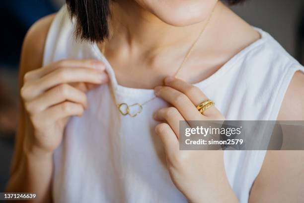 portrait of a gorgeous young asian woman trying on a gold necklace - gold necklace bildbanksfoton och bilder