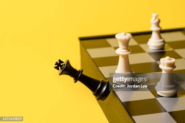 victory, black king chess pieces fall out of chessboard - schachbrett stock-fotos und bilder