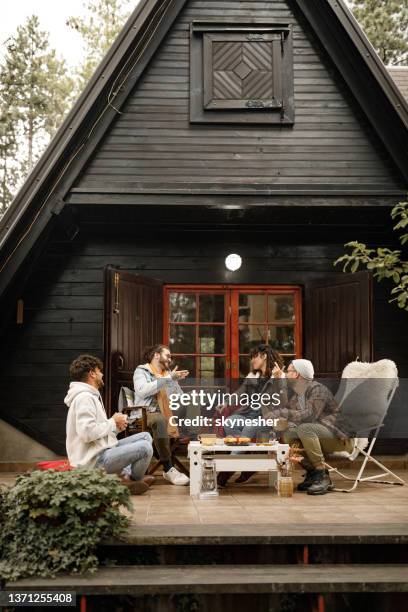 young happy friends talking on a patio in front of cottage. - coffee on patio stock pictures, royalty-free photos & images