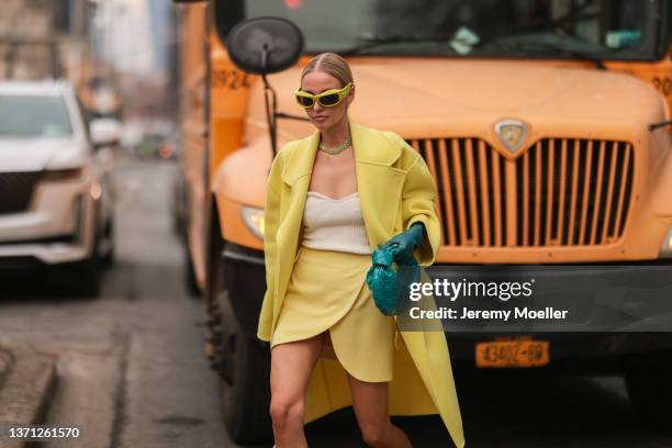 Leonie Hanne seen wearing yellow asymmetric skirt, white top, yellow coat, sunglasses, mint green gloves, Bottega Veneta bag, heels, necklace outside...