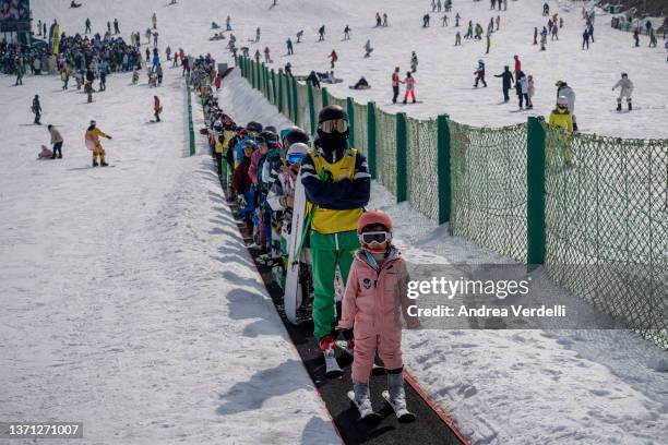 Skiers ride a conveyor at Nanshan ski resort on February 18, 2022 in Beijing, China. Thanks to the Beijing 2022 Winter Olympics, the popularity of...