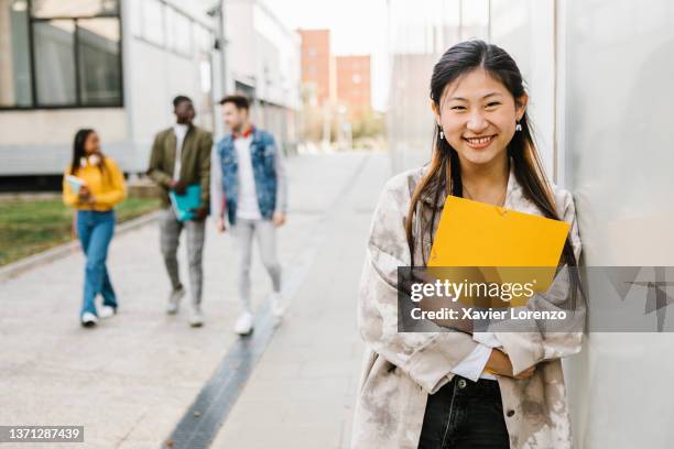 cheerful young asian female student smiling at camera - high school portrait stock-fotos und bilder