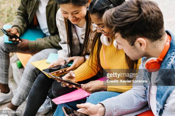 diverse young teenage students having fun using mobile phone in college campus - social media stock pictures, royalty-free photos & images
