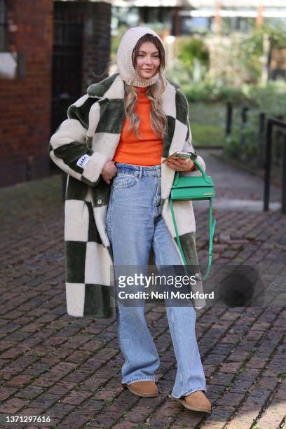 Guest in checkered coat, hood, green handbag attends Bora Aksu at St James the Less Church during London Fashion Week February 2022 on February 18,...