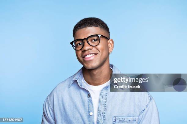 friendly young man wearing denim shirt - portrait young colour background cool stockfoto's en -beelden