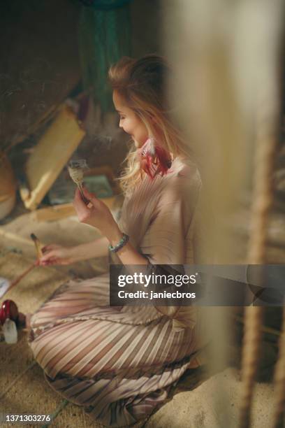 meditative space in desert tent. serene woman smudging with white sage. soul journey - smudging ceremony stock pictures, royalty-free photos & images