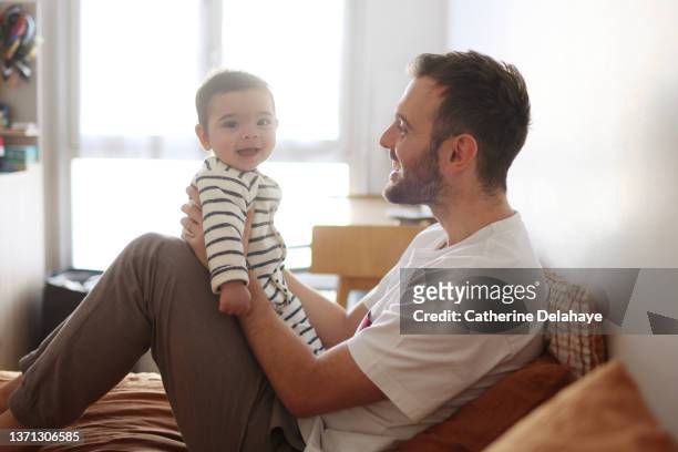 a dad playing with his baby on a bed - métis stock pictures, royalty-free photos & images