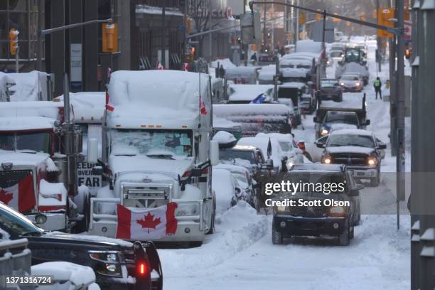 Vehicles drive by trucks participating in a blockade by truck drivers opposing vaccine mandates near Parliament Hill on February 18, 2022 in Ottawa,...