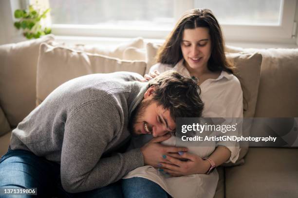 coppia felice che sente i movimenti della pancia del bambino della futura mamma. - man hugging woman foto e immagini stock