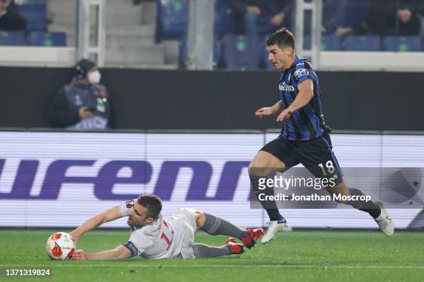 Sokratis Papastathopoulos of Olympiacos FC grabs the ball as he tumbles to the ground in a race with Ruslan Malinovskyi of Atalanta only to have a...