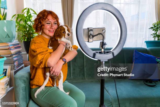 excited influencer doing a vlog post in her living room with her dog - filming tutorial stock pictures, royalty-free photos & images