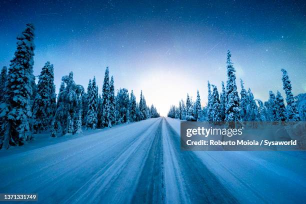 icy road in the arctic forest under the stars, lapland - winter road stock pictures, royalty-free photos & images