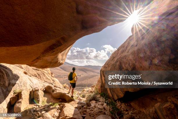 hiker man exploring a rock cave, fuerteventura - fuerteventura stock-fotos und bilder
